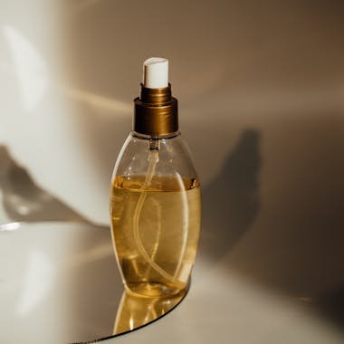 Close-up of a perfume bottle elegantly placed on a reflective surface with warm lighting.