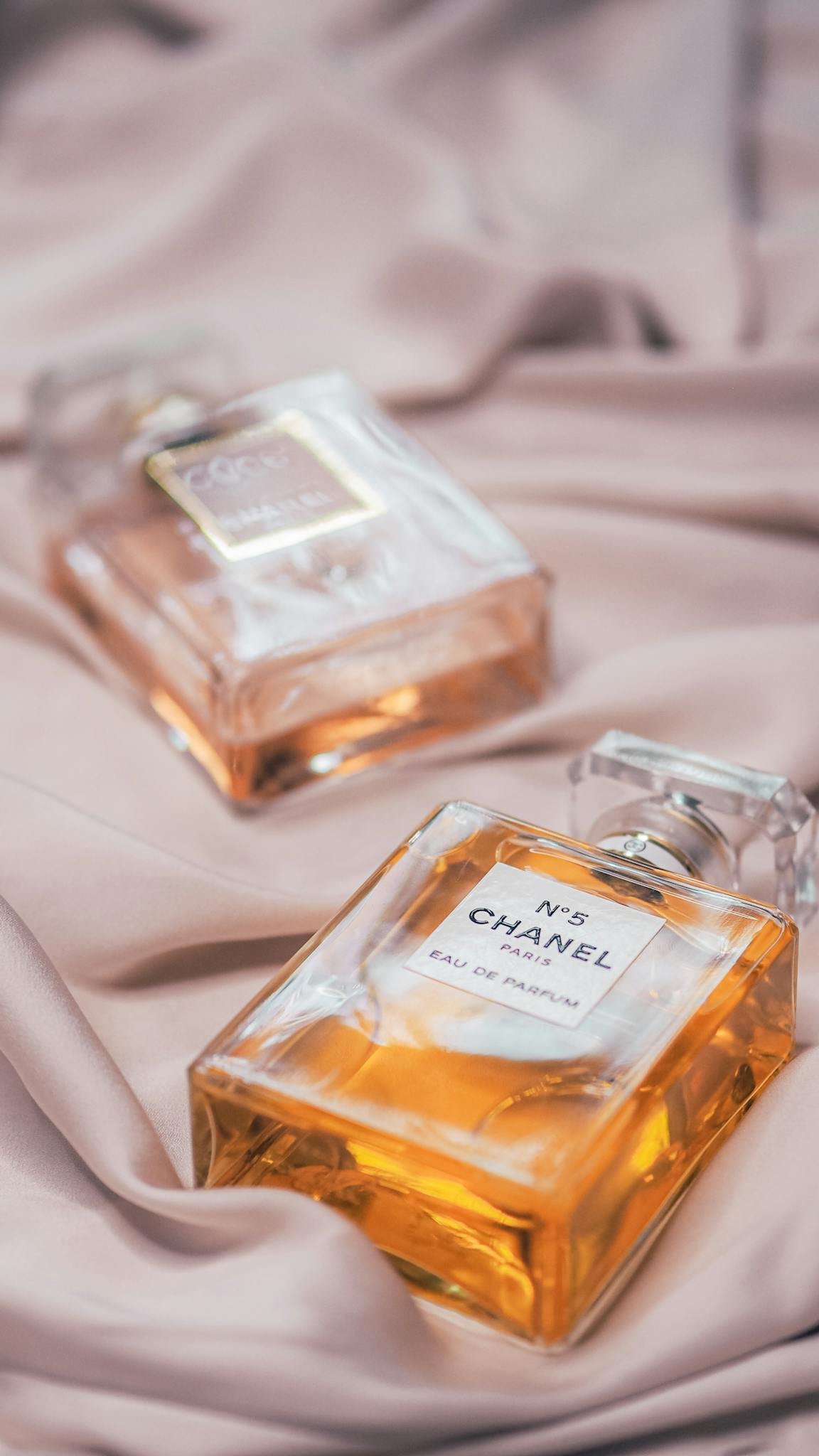 Close-up of Chanel perfumes on silky fabric, showcasing elegance and luxury in a stylish arrangement.