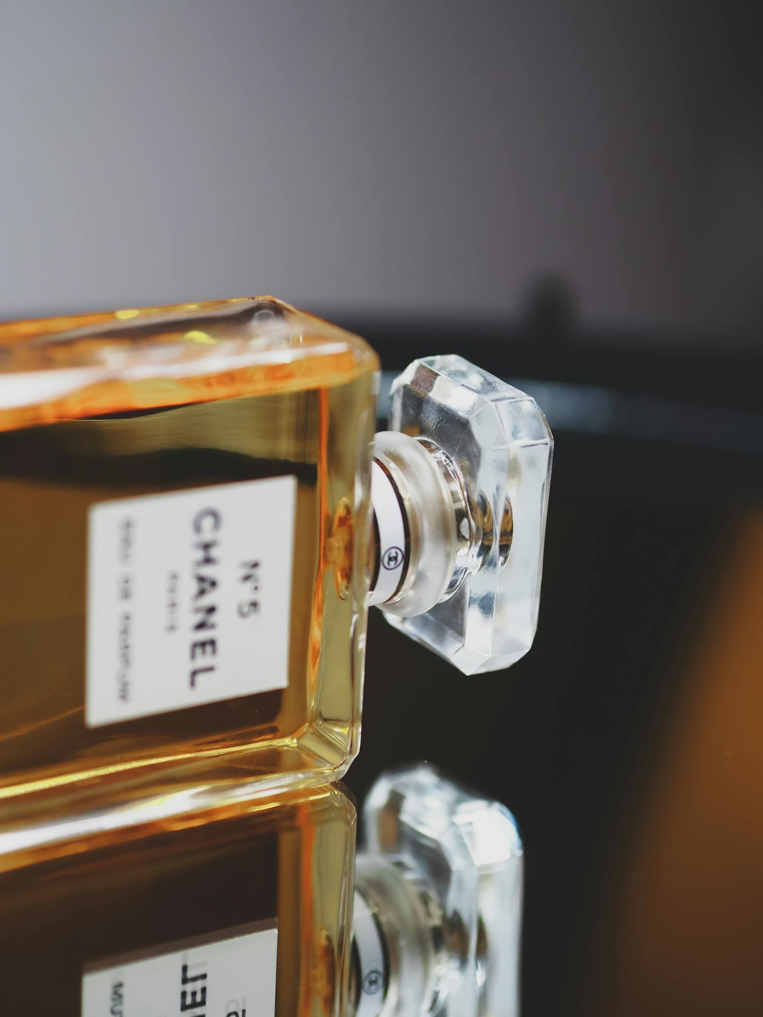 Elegant close-up of Chanel No.5 perfume bottle with reflective surface, showcasing luxury aroma.